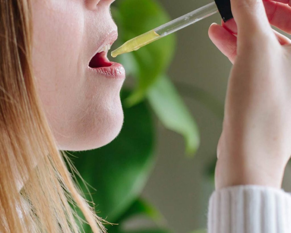 Person taking CBD oil sublingually for wellness balance